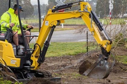 Excavator cutting a cable trench across open ground