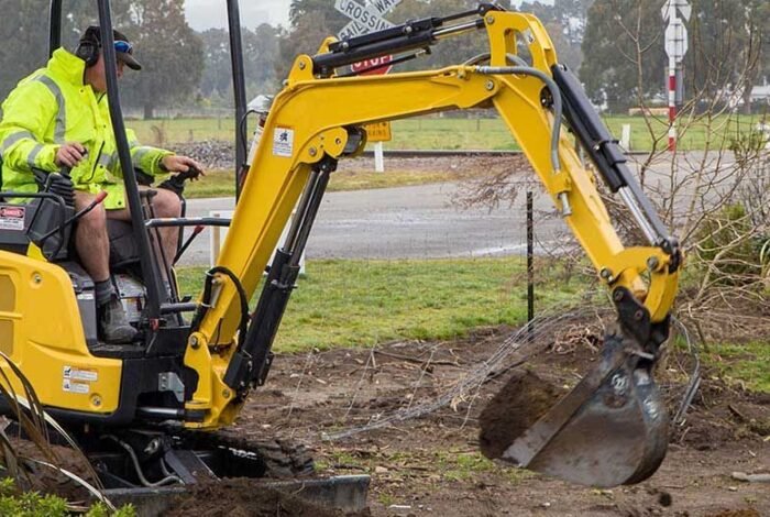 Excavator cutting a cable trench across open ground