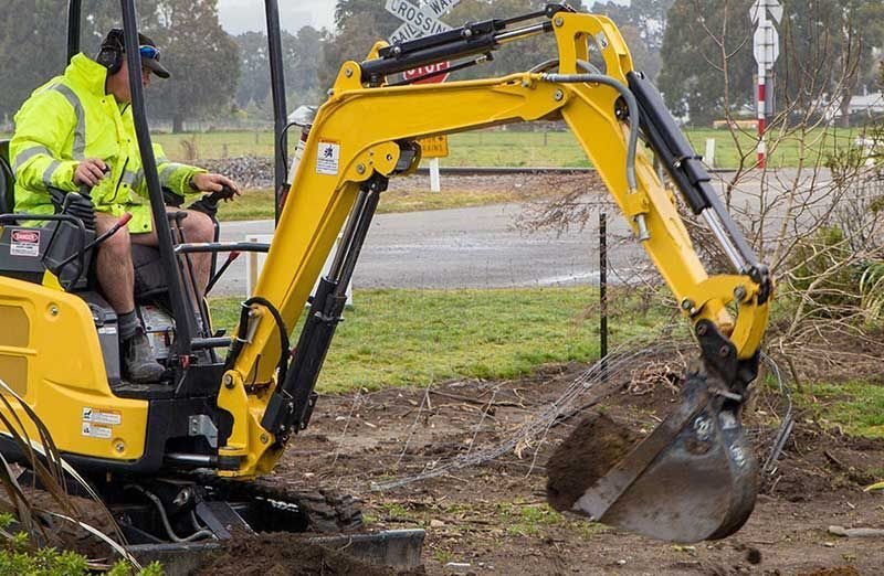 Excavator cutting a cable trench across open ground